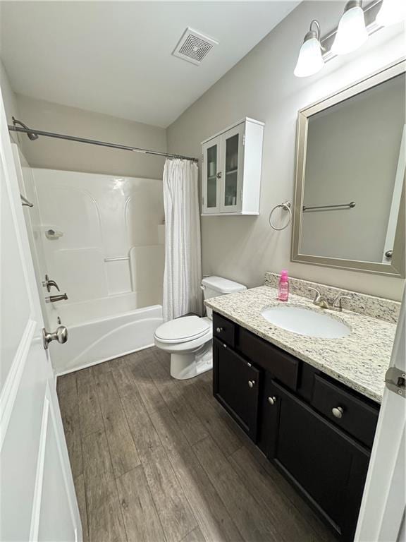 full bath featuring visible vents, toilet, wood finished floors, shower / bath combination with curtain, and vanity