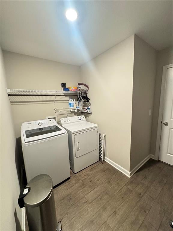 laundry area featuring laundry area, baseboards, washer and dryer, and wood finished floors