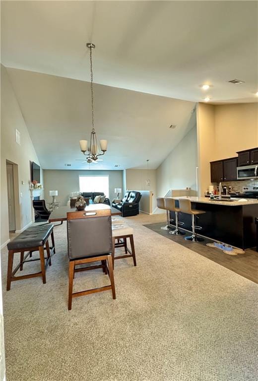 living area with light carpet, an inviting chandelier, visible vents, and high vaulted ceiling