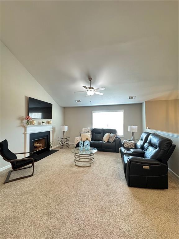 living area with ceiling fan, a fireplace with flush hearth, carpet flooring, visible vents, and baseboards