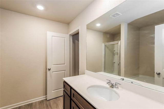 bathroom with vanity, hardwood / wood-style flooring, and a shower with door