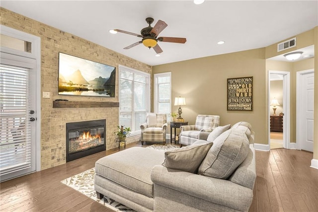 living room with hardwood / wood-style flooring, ceiling fan, and a fireplace