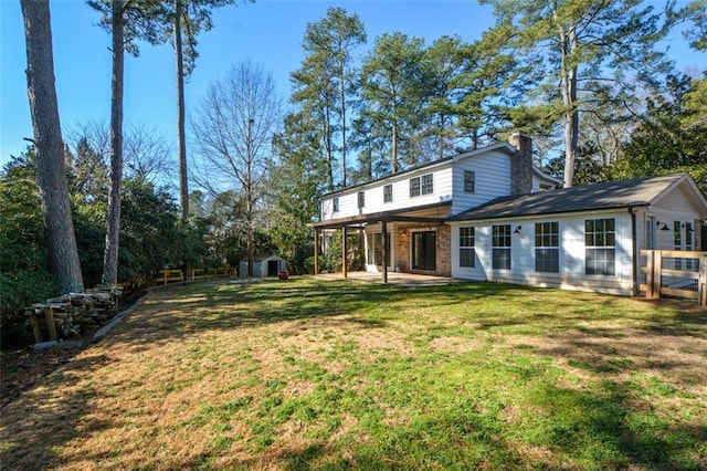 rear view of house with a yard and a storage shed