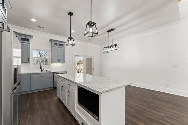 kitchen with a center island, pendant lighting, stainless steel appliances, visible vents, and a sink