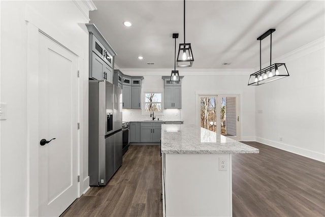 kitchen featuring pendant lighting, gray cabinetry, a kitchen island, light stone countertops, and stainless steel fridge