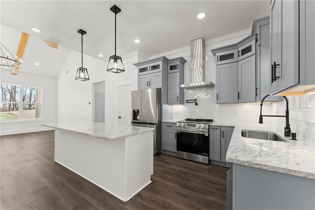 kitchen featuring a sink, a kitchen island, hanging light fixtures, appliances with stainless steel finishes, and wall chimney exhaust hood