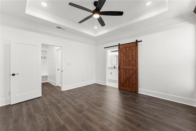 unfurnished bedroom featuring a tray ceiling, visible vents, dark wood finished floors, and a barn door