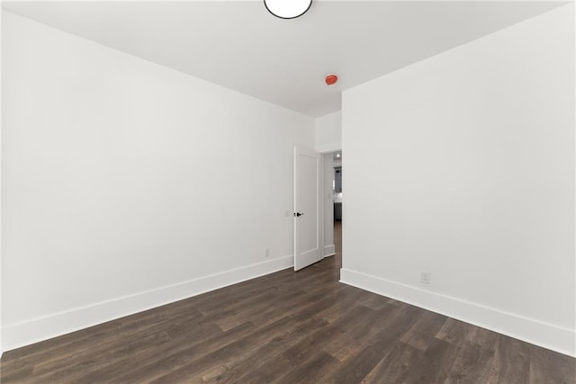 unfurnished room featuring dark wood-style floors and baseboards