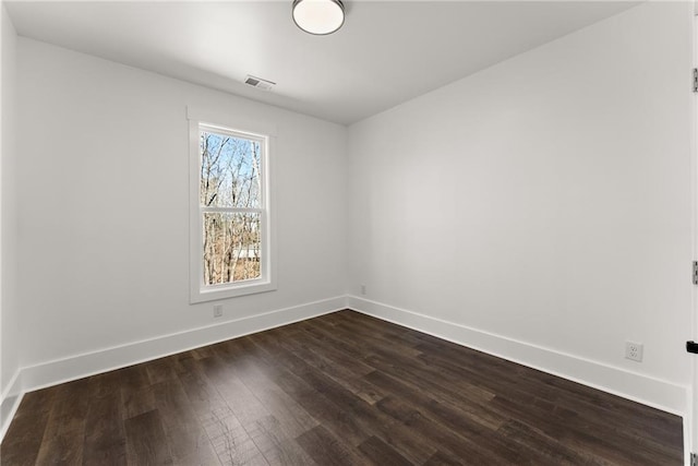 spare room featuring visible vents, baseboards, and dark wood finished floors