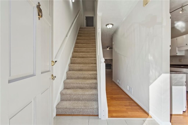 stairs with hardwood / wood-style flooring and track lighting