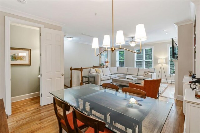 dining space with light wood-style floors, baseboards, ornamental molding, and a chandelier