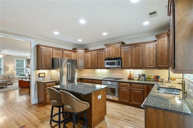 kitchen with visible vents, a center island, light wood-type flooring, dark stone counters, and stainless steel appliances