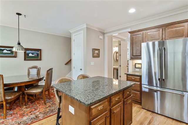 kitchen with light wood-style floors, a center island, dark stone counters, and high end fridge