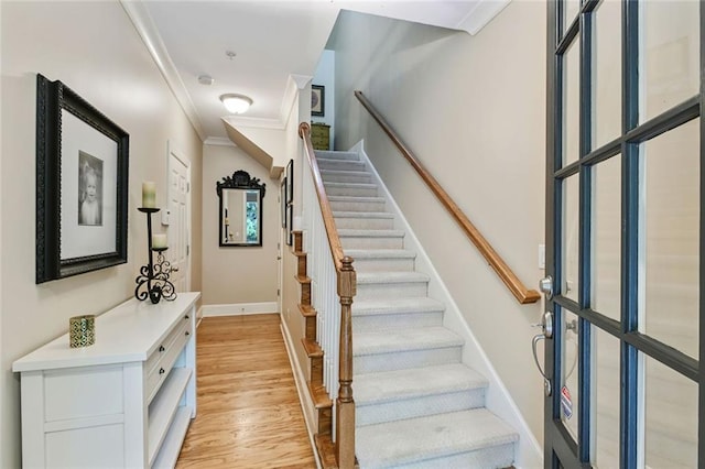 stairs with crown molding, baseboards, and wood finished floors