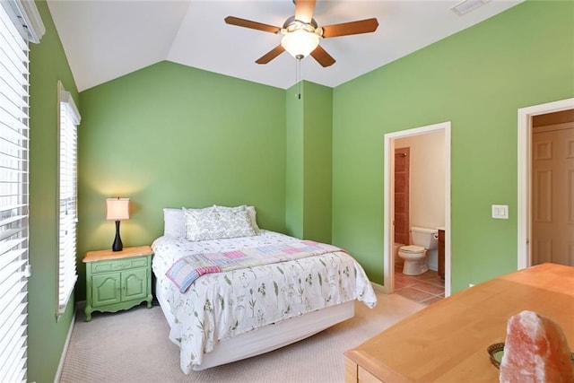 bedroom with light carpet, visible vents, ensuite bath, a ceiling fan, and vaulted ceiling