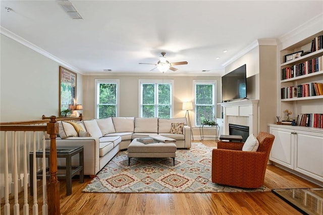 living area with visible vents, a glass covered fireplace, ceiling fan, and a healthy amount of sunlight