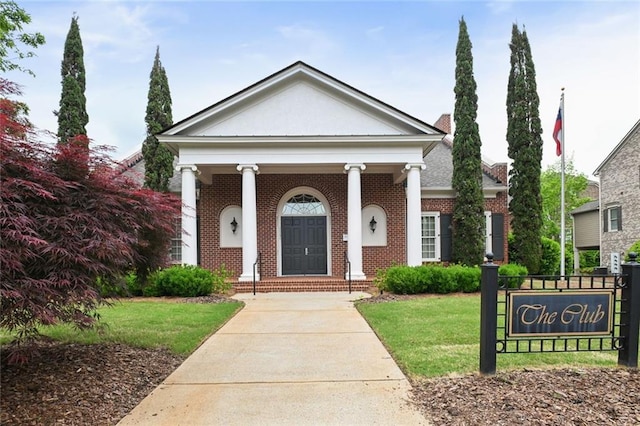 greek revival inspired property with brick siding and a front lawn
