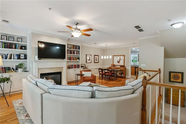 living area with visible vents, a ceiling fan, crown molding, and light wood-type flooring