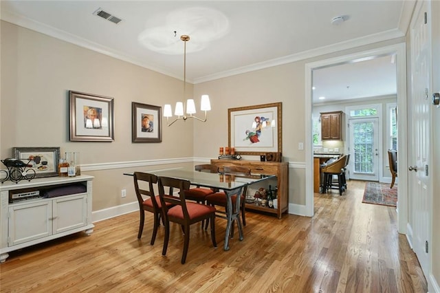 dining area featuring crown molding, a notable chandelier, baseboards, light wood-type flooring, and visible vents