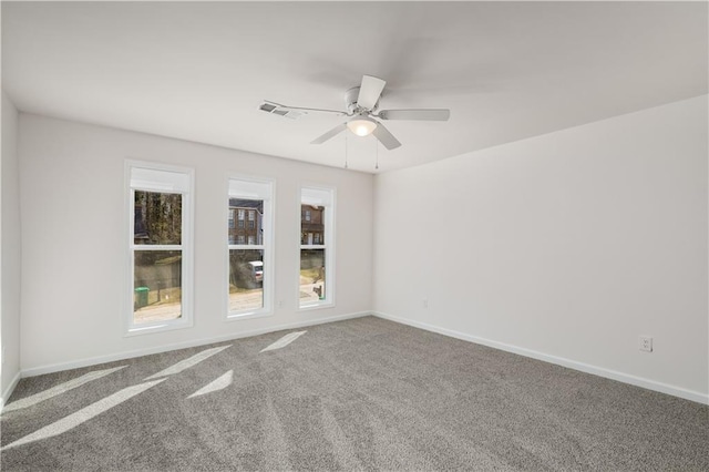 unfurnished room featuring carpet floors, visible vents, baseboards, and a ceiling fan