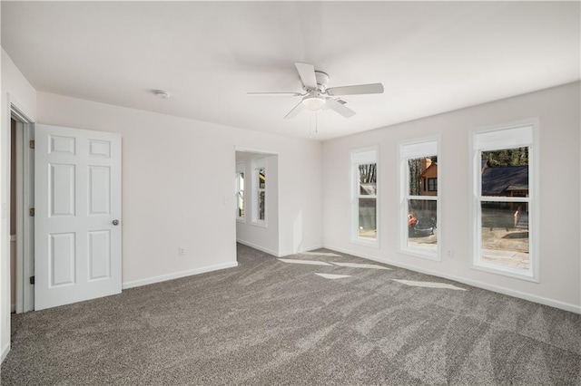 carpeted spare room featuring a ceiling fan and baseboards