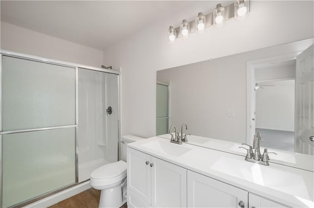 bathroom featuring toilet, a shower stall, double vanity, and a sink