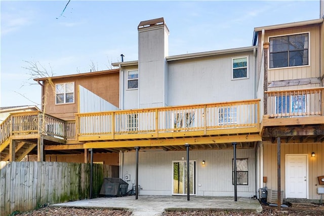 back of house with a patio area, a chimney, fence, and a wooden deck