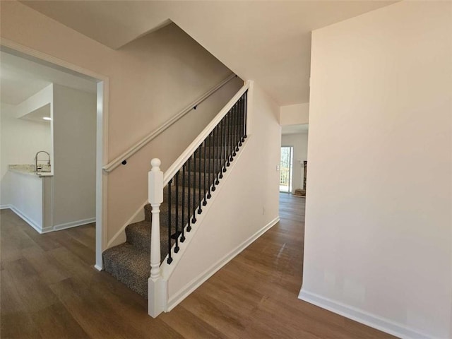 stairs with hardwood / wood-style floors and sink