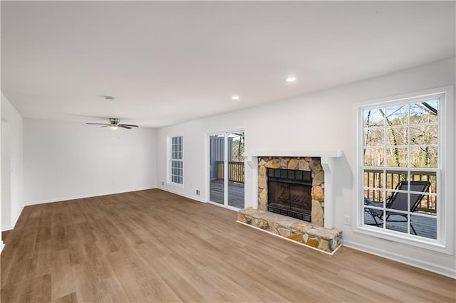 unfurnished living room with light wood finished floors, a fireplace, recessed lighting, and baseboards