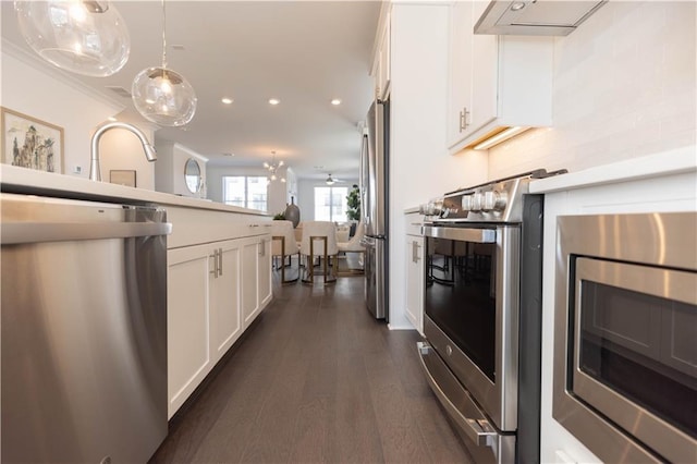 kitchen with stainless steel appliances, hanging light fixtures, dark hardwood / wood-style floors, crown molding, and white cabinets