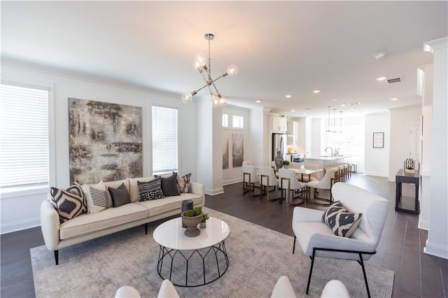 living room with a chandelier, plenty of natural light, dark wood-type flooring, and sink