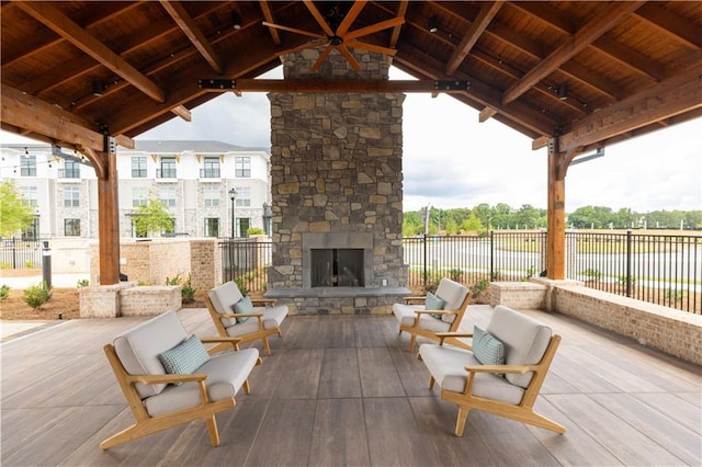 view of patio with a gazebo, an outdoor stone fireplace, and ceiling fan