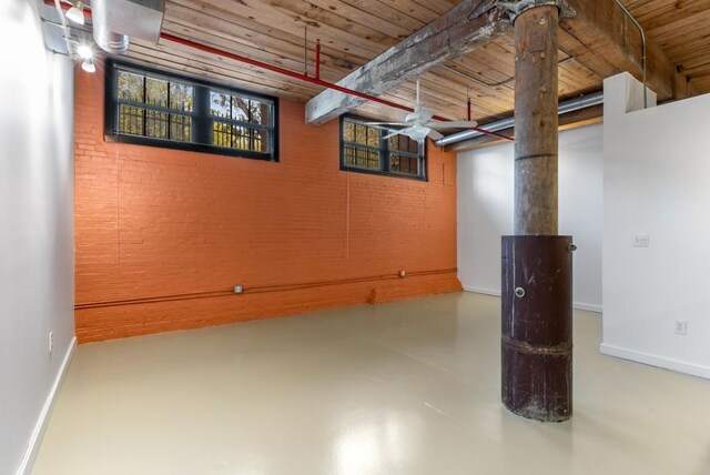 basement with brick wall, wooden ceiling, and baseboards
