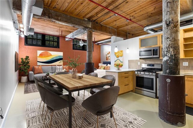 kitchen featuring stainless steel appliances, a peninsula, tasteful backsplash, a ceiling fan, and concrete flooring