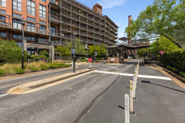 view of street featuring traffic signs, a gated entry, curbs, and a gate