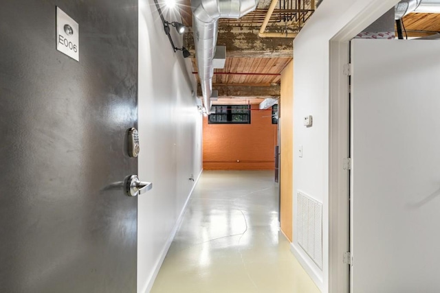 corridor with beamed ceiling, baseboards, visible vents, and concrete floors