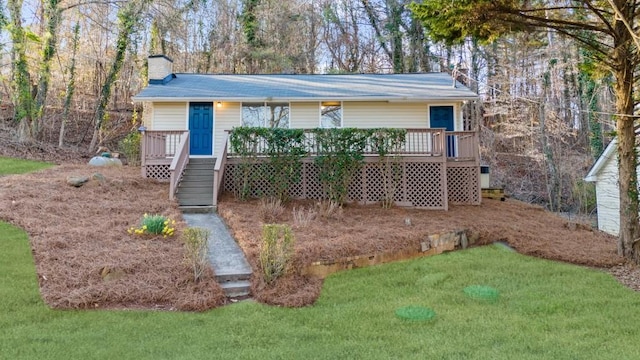 view of front of home featuring a wooden deck, a front lawn, and a chimney