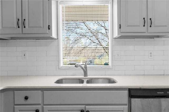 kitchen with a sink, tasteful backsplash, stainless steel dishwasher, and light countertops