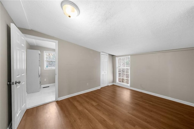 interior space with a textured ceiling, baseboards, and wood finished floors