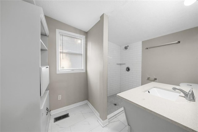 full bathroom featuring visible vents, baseboards, tiled shower, marble finish floor, and a textured ceiling