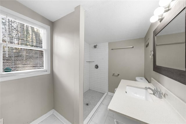 full bathroom featuring vanity, baseboards, a tile shower, a textured ceiling, and marble finish floor