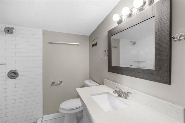 bathroom featuring a tile shower, a textured ceiling, toilet, and vanity