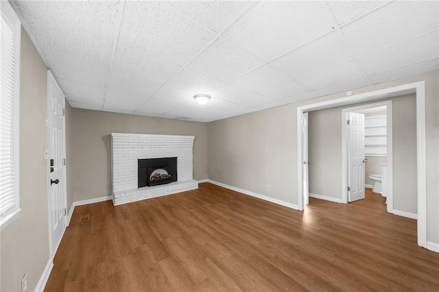 unfurnished living room with a fireplace, wood finished floors, and baseboards