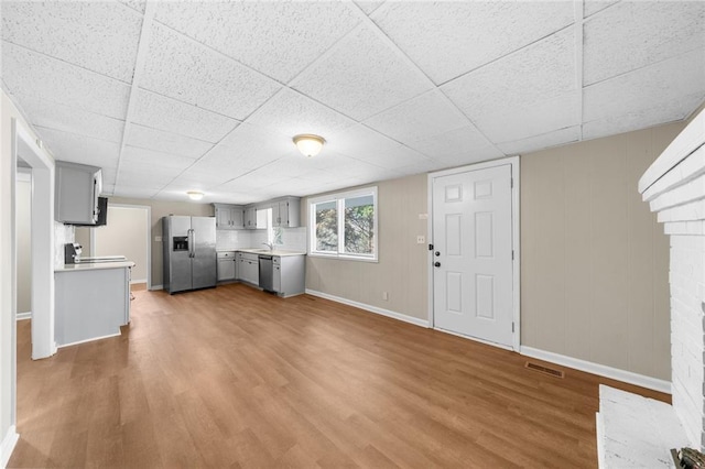 interior space with a drop ceiling, visible vents, baseboards, and wood finished floors