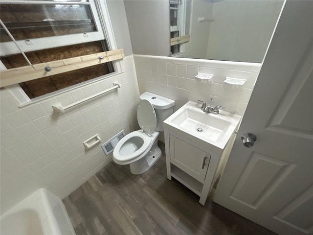 bathroom featuring hardwood / wood-style floors, vanity, toilet, and tile walls