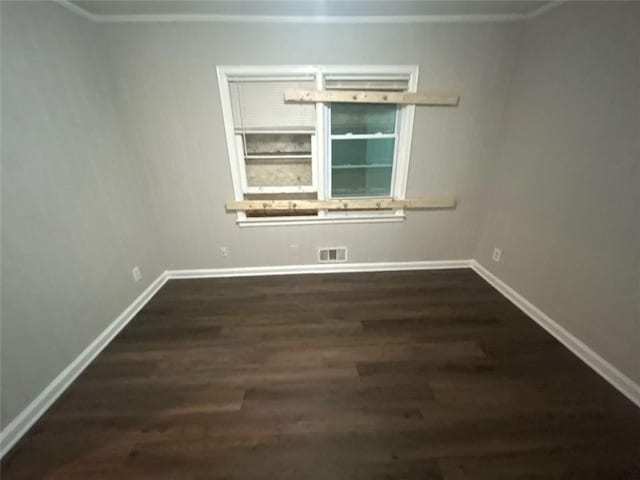 spare room featuring dark hardwood / wood-style floors and crown molding