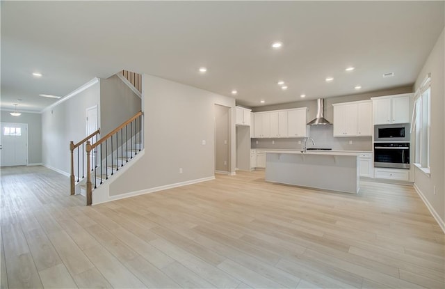 616 Gratton Ln, Mcdonough, GA 30253 - kitchen with wall oven, stainless steel microwave, wall chimney exhaust hood, open floor plan, and a center island with sink