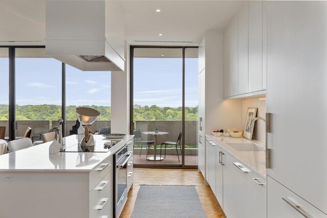 kitchen featuring sink, black electric stovetop, a kitchen island, and white cabinetry