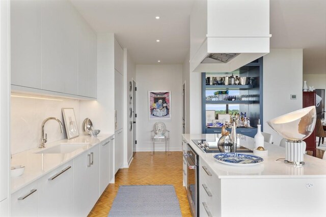 kitchen featuring white cabinets, sink, and light parquet flooring