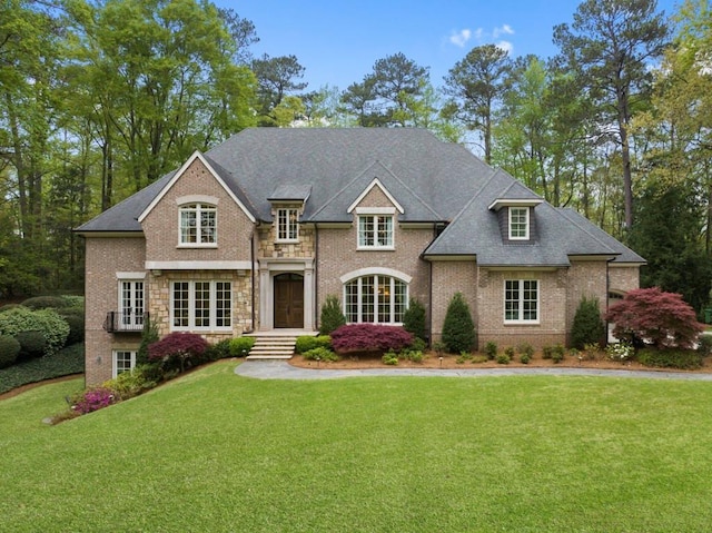 french provincial home featuring stone siding, a front lawn, and brick siding